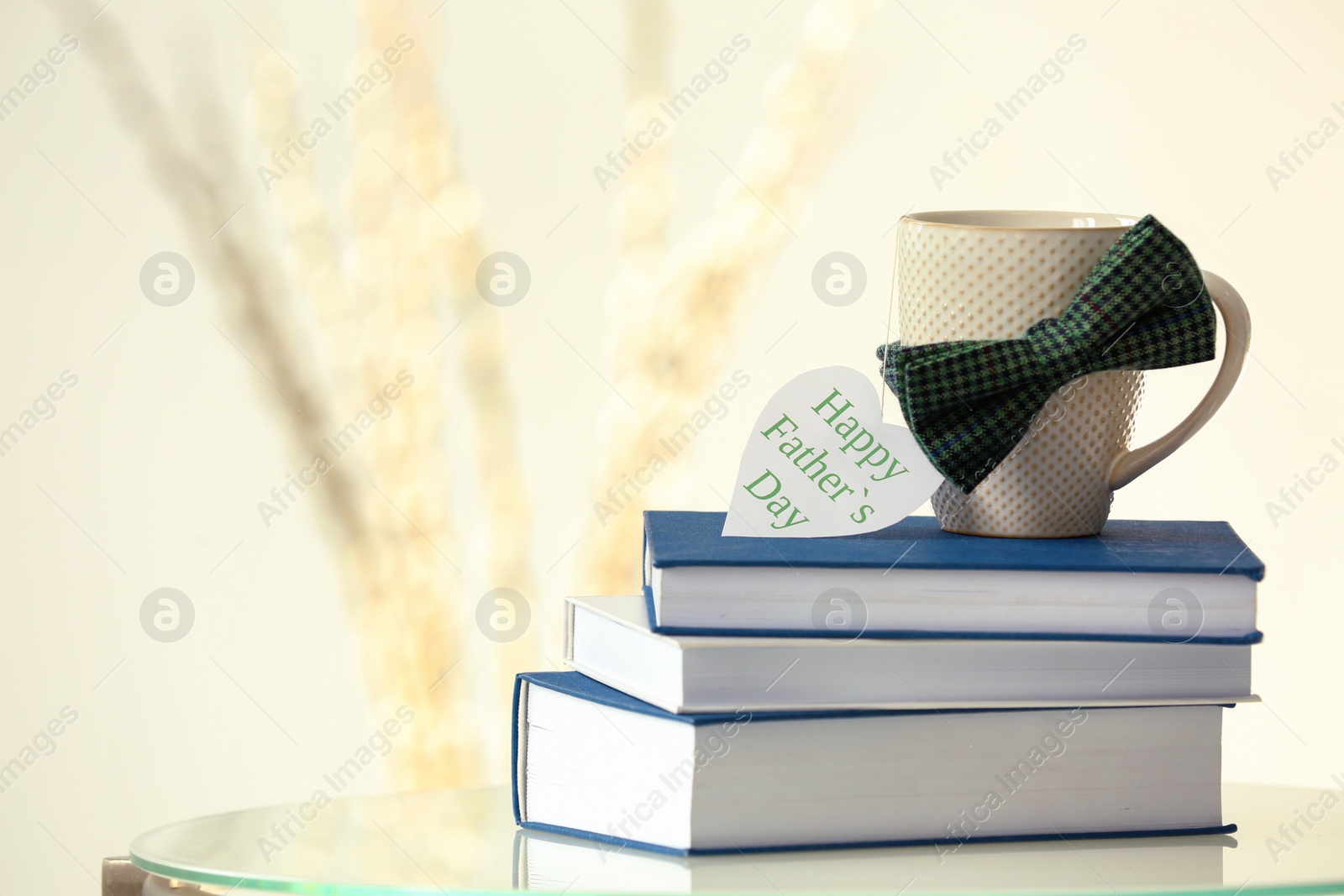 Photo of Cup, books and bow tie on table. Father's day celebration