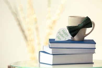 Photo of Cup, books and bow tie on table. Father's day celebration