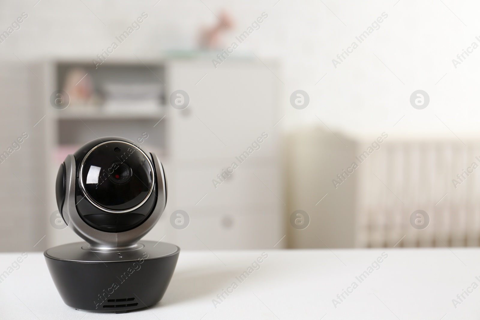 Photo of Baby camera on table in room, space for text. Video nanny