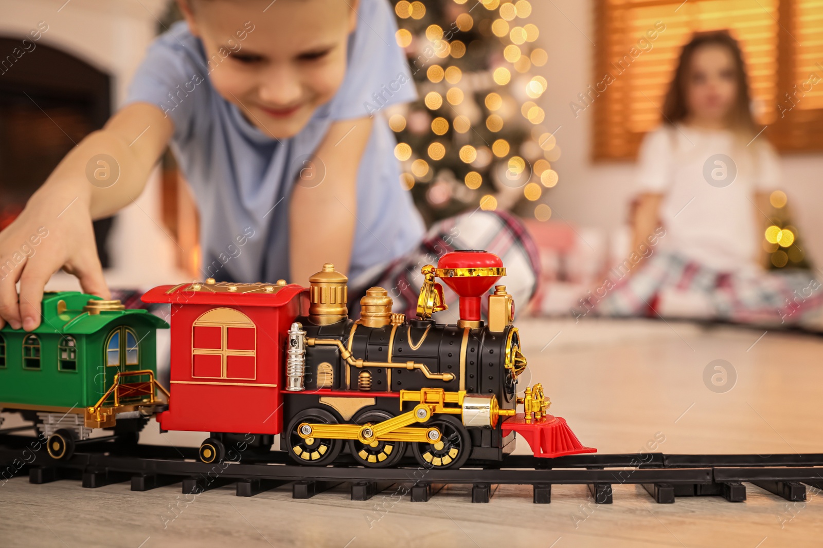 Photo of Children playing with colorful toy in room decorated for Christmas, focus on train