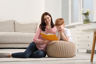 Happy mother reading book with her child at home
