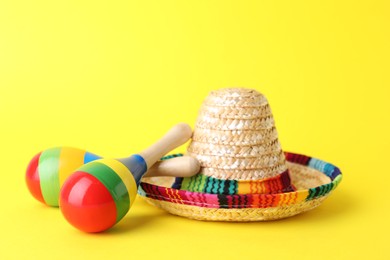 Photo of Colorful maracas and sombrero hat on yellow background. Musical instrument