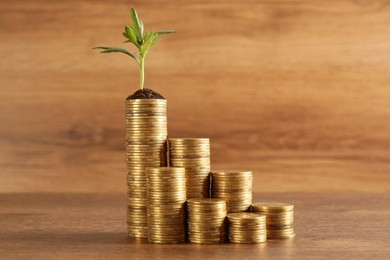 Photo of Stacked coins and green sprout on wooden table. Investment concept