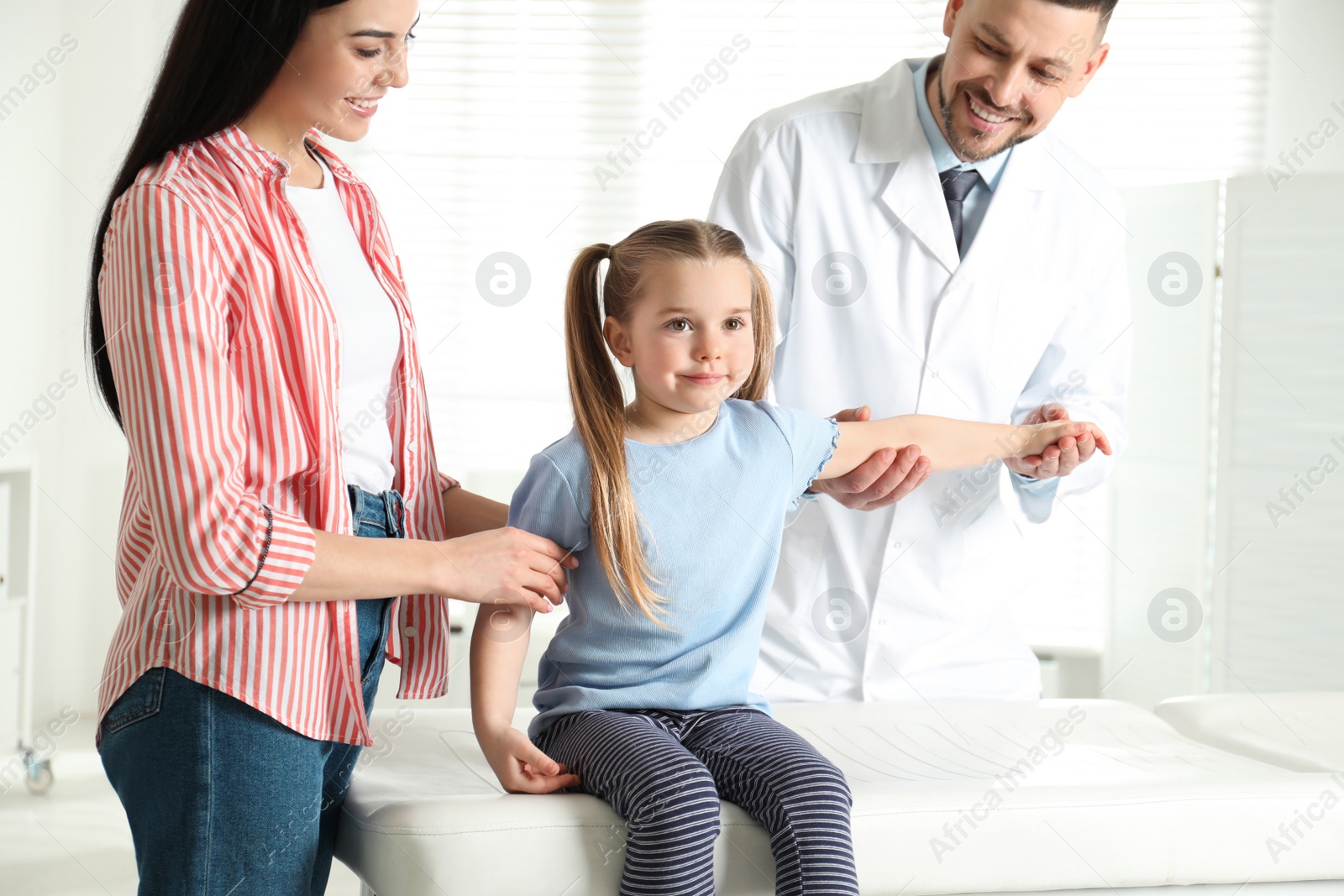 Photo of Professional orthopedist examining little patient's arm in clinic