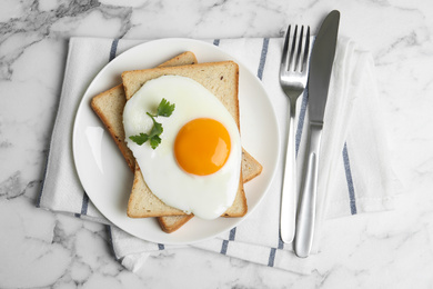 Photo of Tasty fried egg with bread on white marble table, flat lay