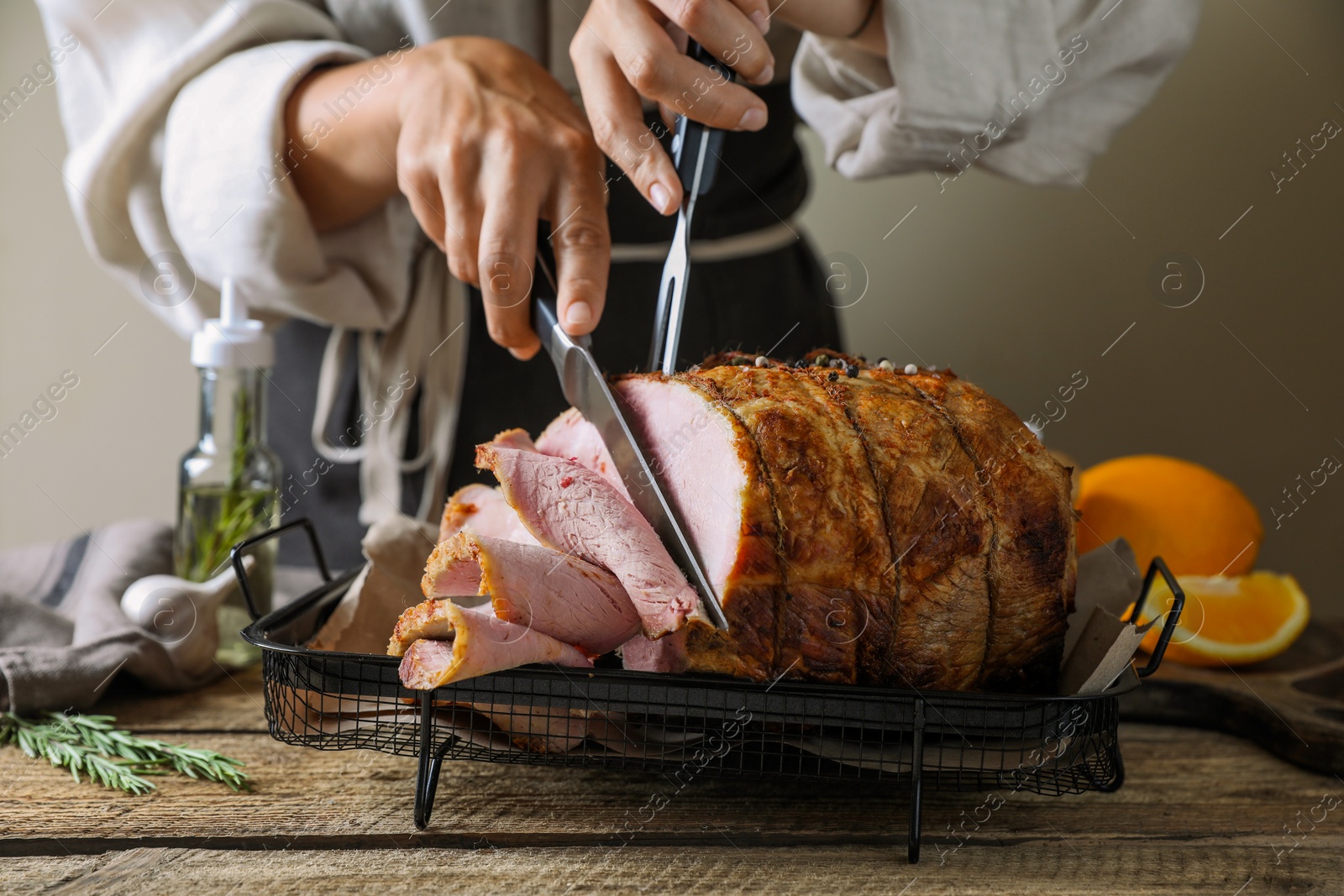 Photo of Woman cutting delicious baked ham at wooden table, closeup