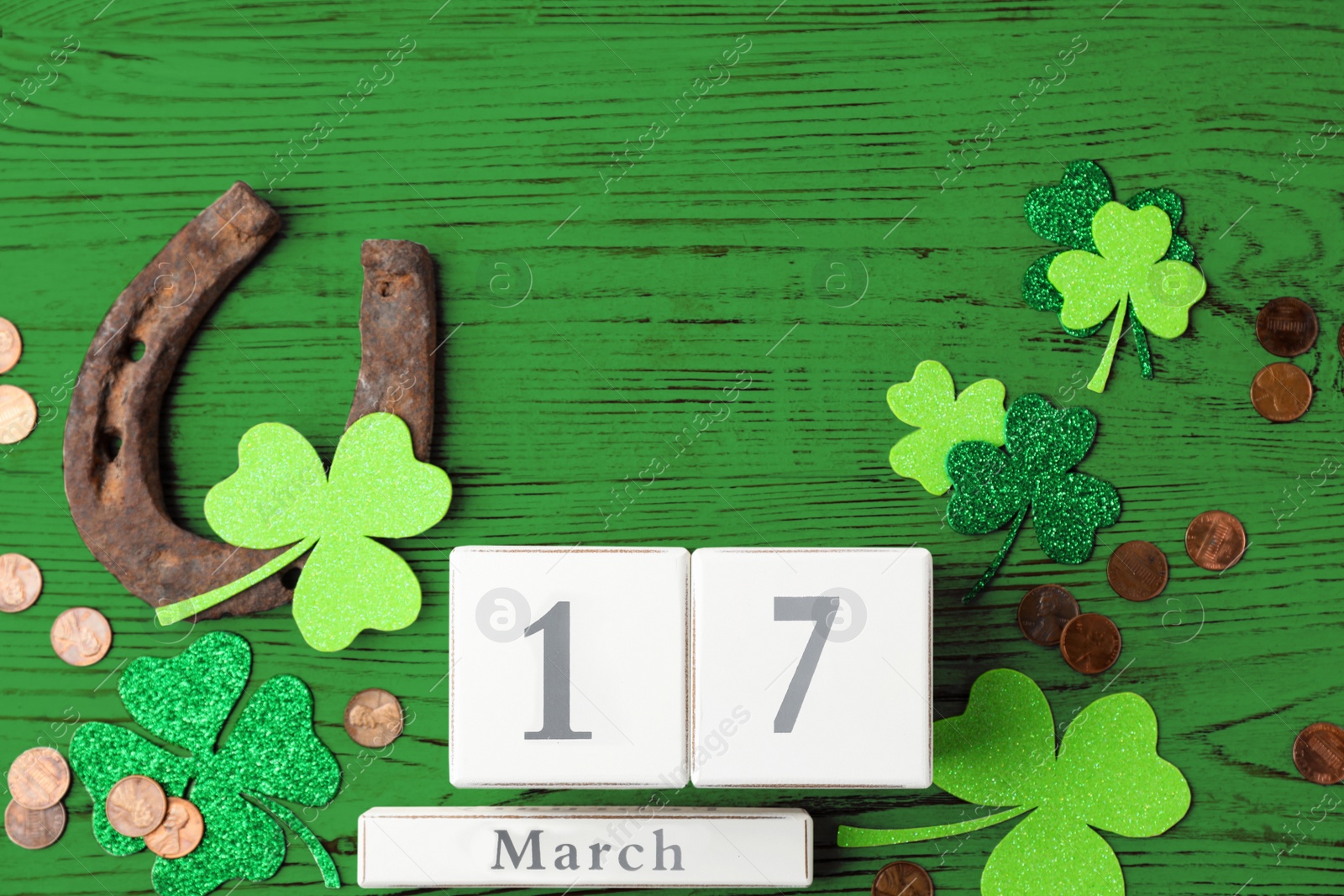 Image of Flat lay composition with horseshoe and block calendar on green wooden background. St. Patrick's Day celebration