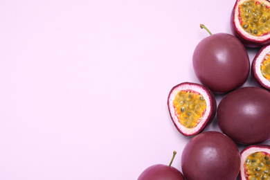 Fresh ripe passion fruits (maracuyas) on light pink background, flat lay. Space for text