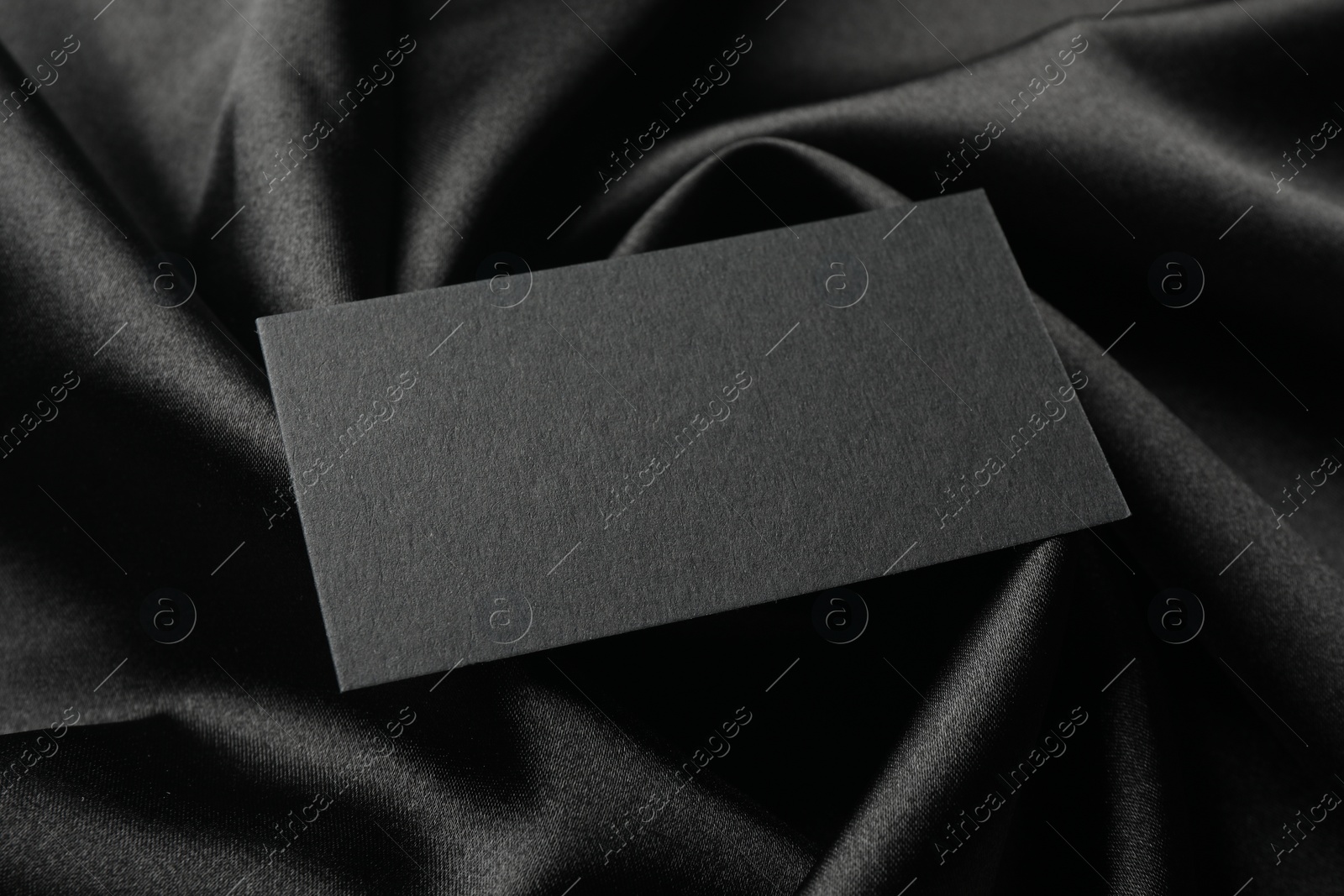 Photo of Blank business card on black fabric, closeup. Mockup for design