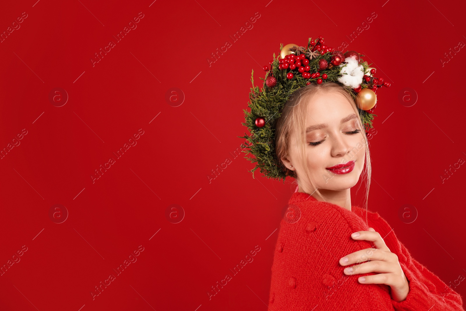 Photo of Beautiful young woman wearing Christmas wreath on red background. Space for text