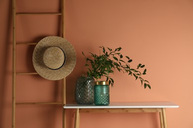 Stylish decorative vases on table near wall