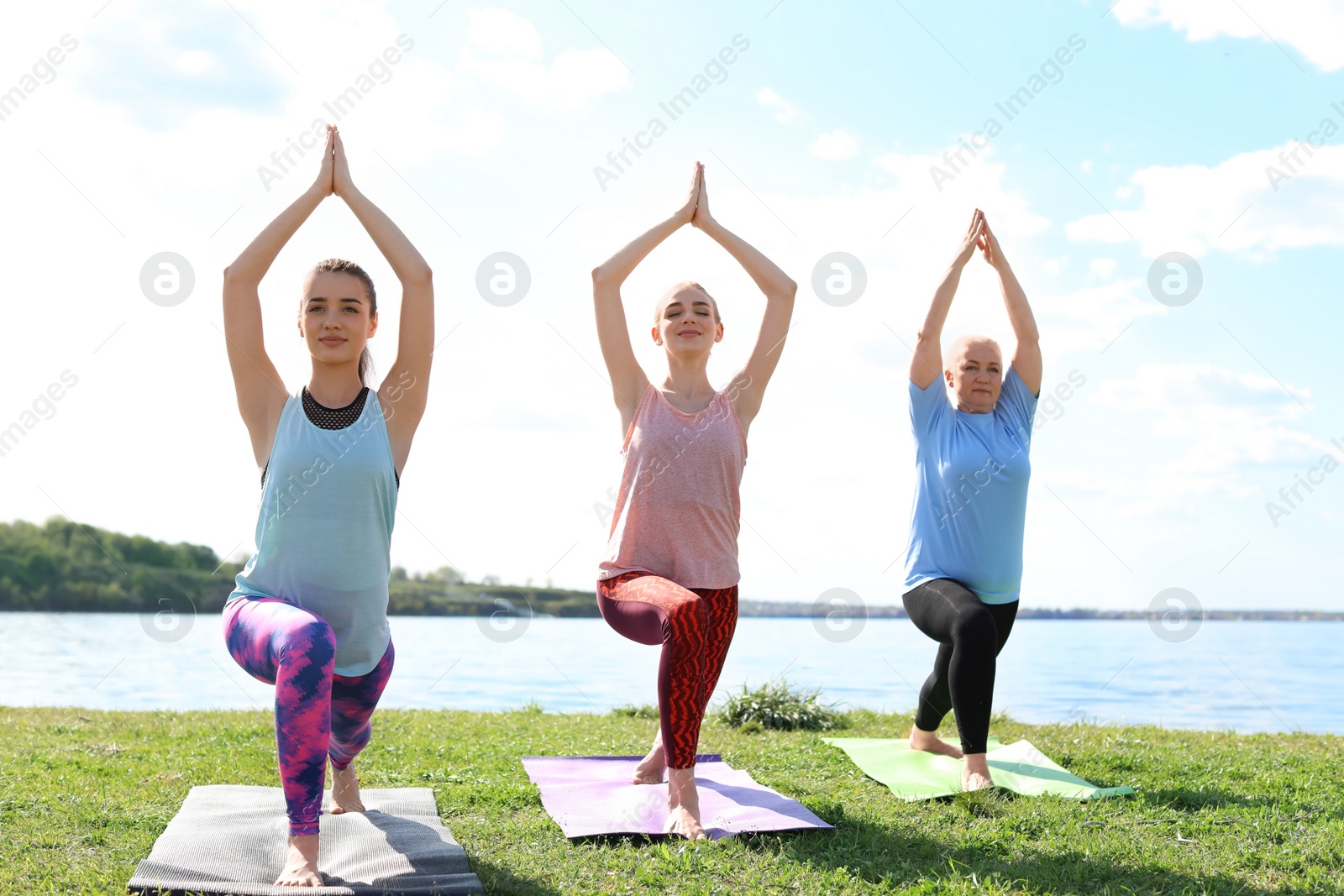 Photo of Group of women practicing yoga near river on sunny day