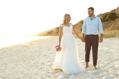 Wedding couple holding hands together on beach. Space for text