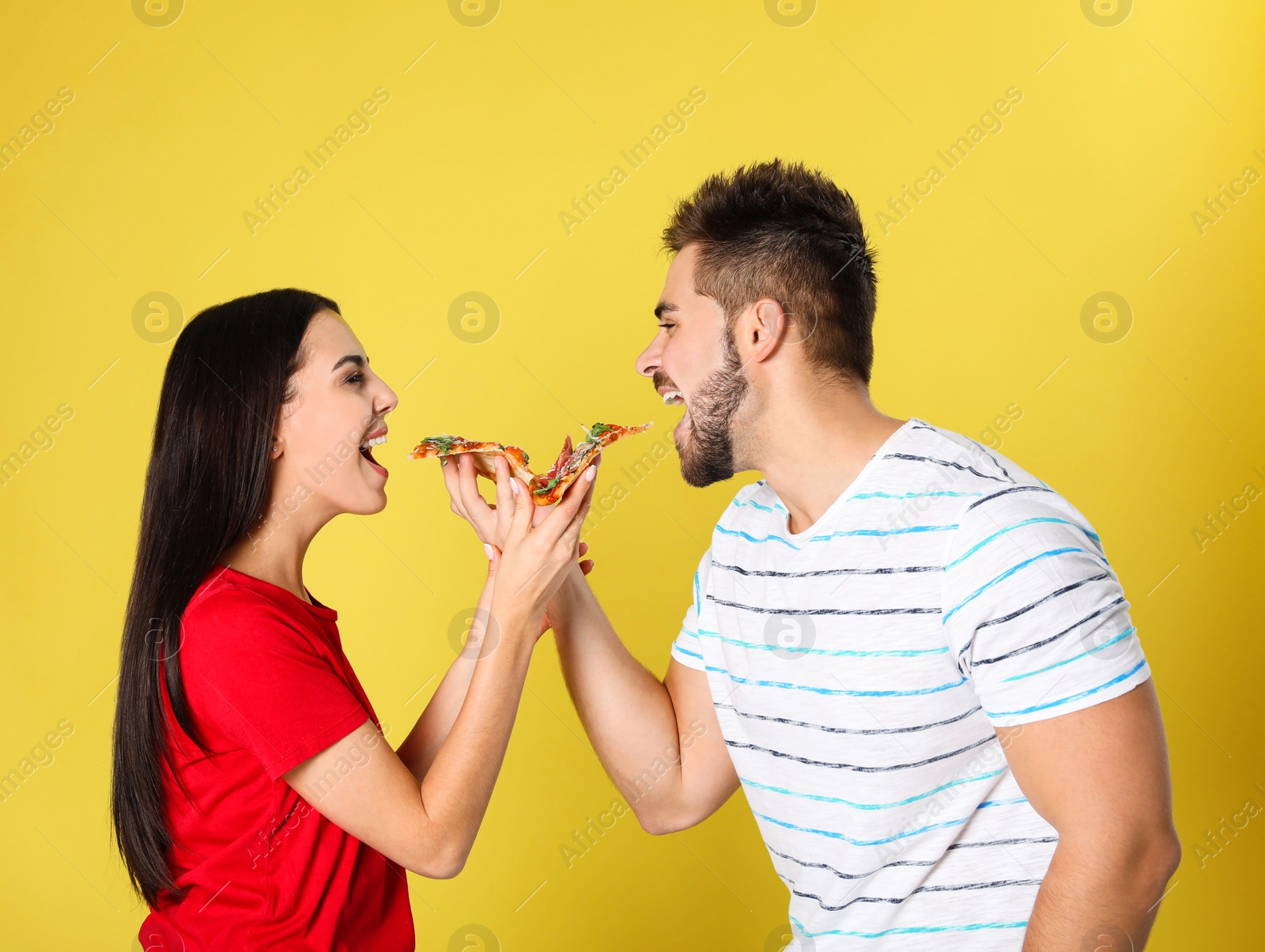 Photo of Young couple with pizza on yellow background