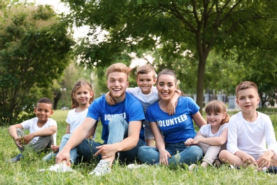 Volunteers and kids sitting on grass in park