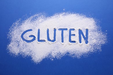 Word Gluten written with flour on blue background, top view
