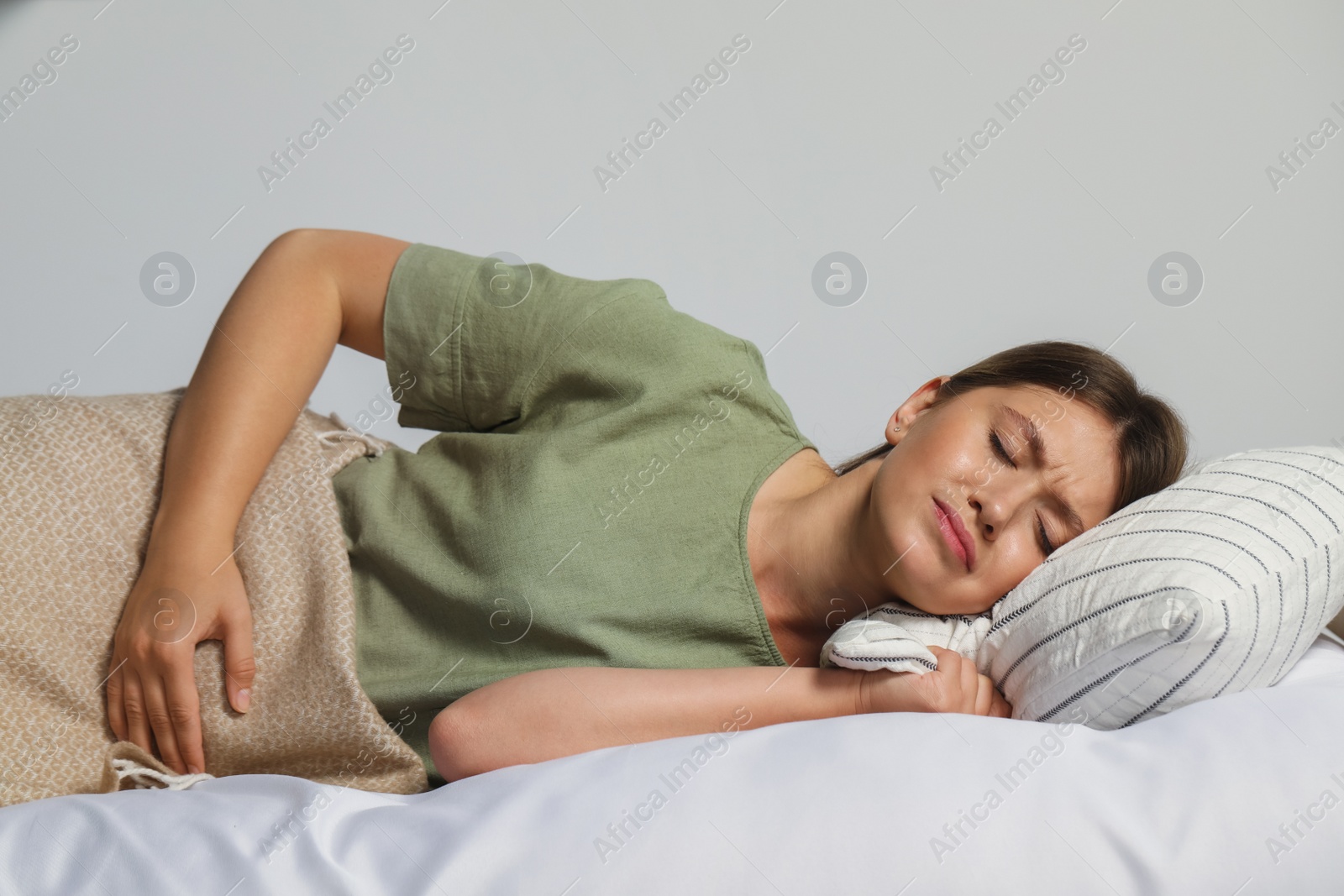 Photo of Young woman suffering from menstrual pain in bed at home