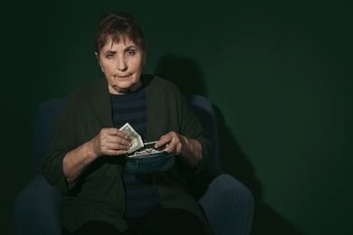 Photo of Poor senior woman with money on color background. Space for text