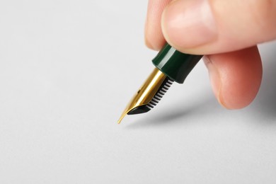 Photo of Woman with fountain pen above white paper, closeup. Space for text