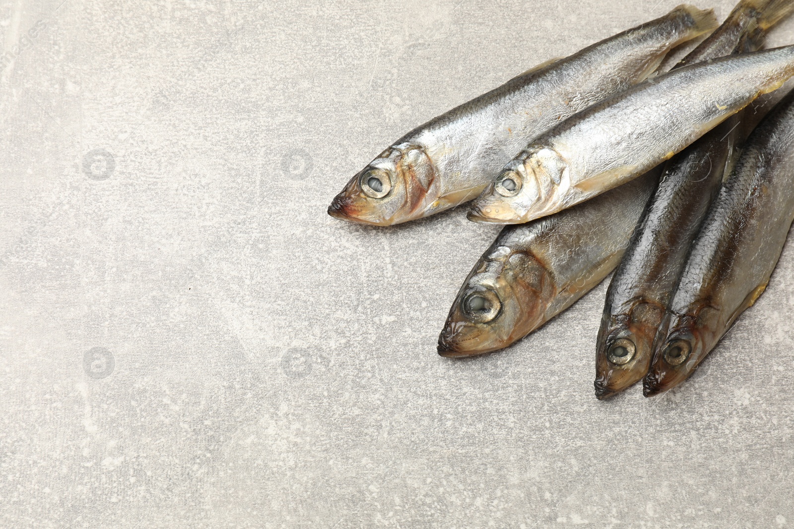 Photo of Fresh raw sprats on grey table, above view. Space for text