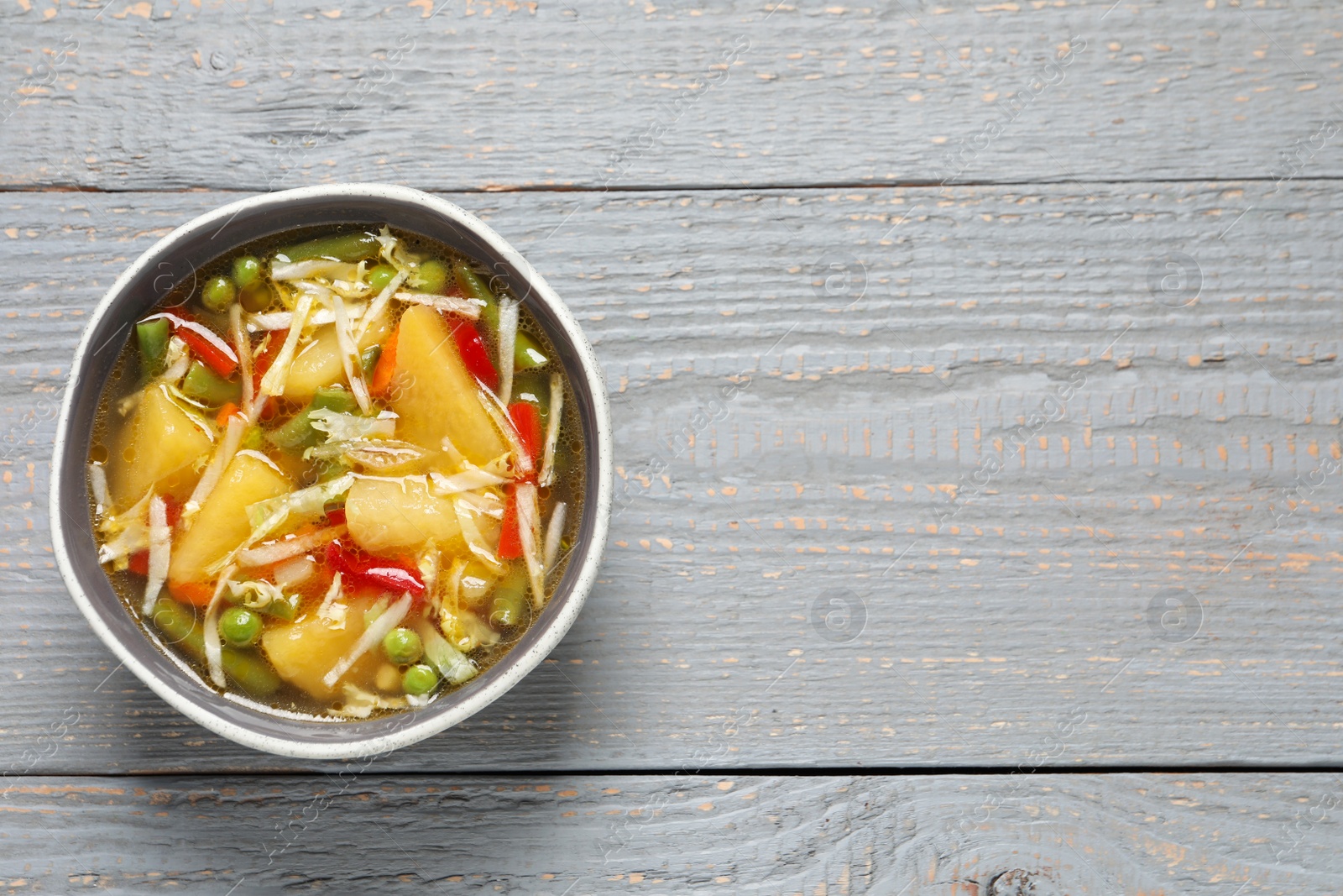 Photo of Bowl of delicious turnip soup on grey wooden table, top view. Space for text