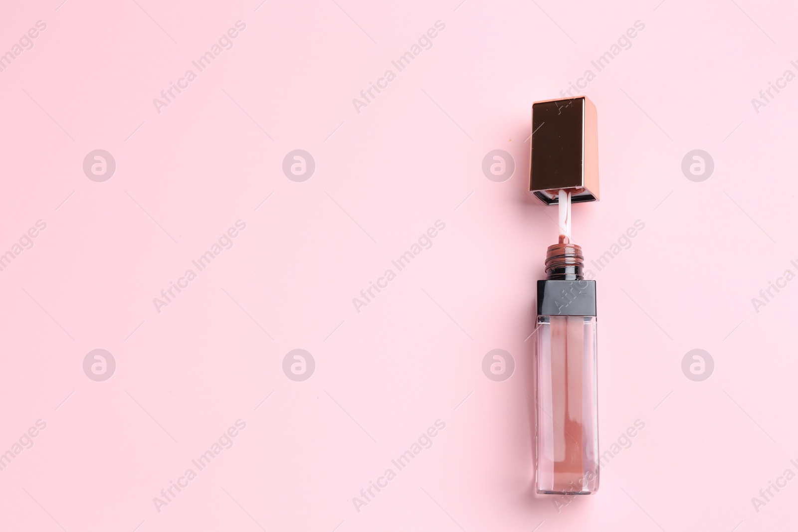 Photo of Bright lip gloss on pink background, top view. Space for text