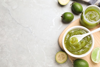 Feijoa jam and fruit on light grey marble table, flat lay. Space for text