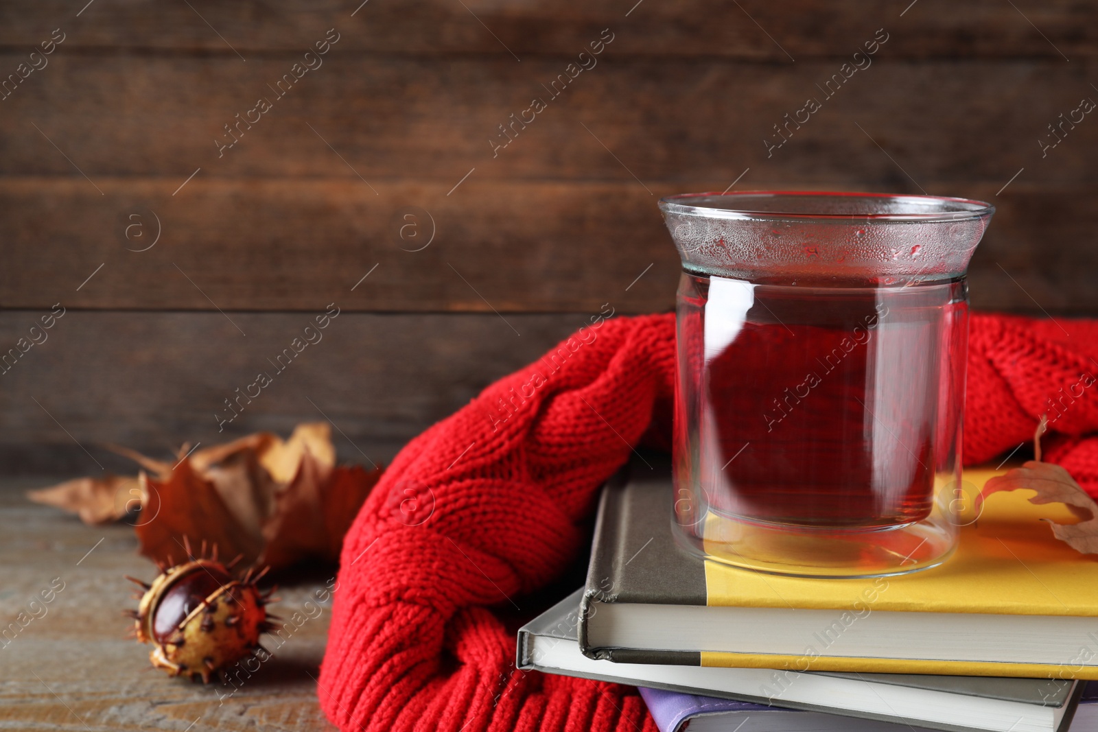 Photo of Cup of hot drink and books on wooden table, space for text. Cozy autumn atmosphere