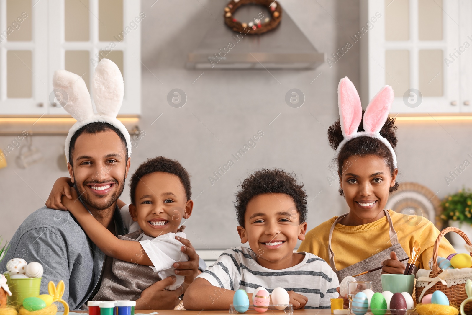 Photo of Happy African American family painting Easter eggs at table in kitchen