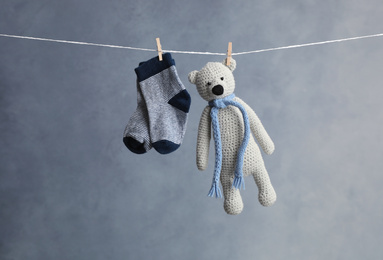 Photo of Pair of child's socks and toy bear hanging on laundry line against dark background