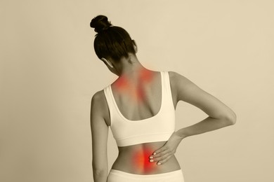 Woman suffering from back pain on color background