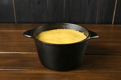Photo of Fondue pot with melted cheese on wooden table