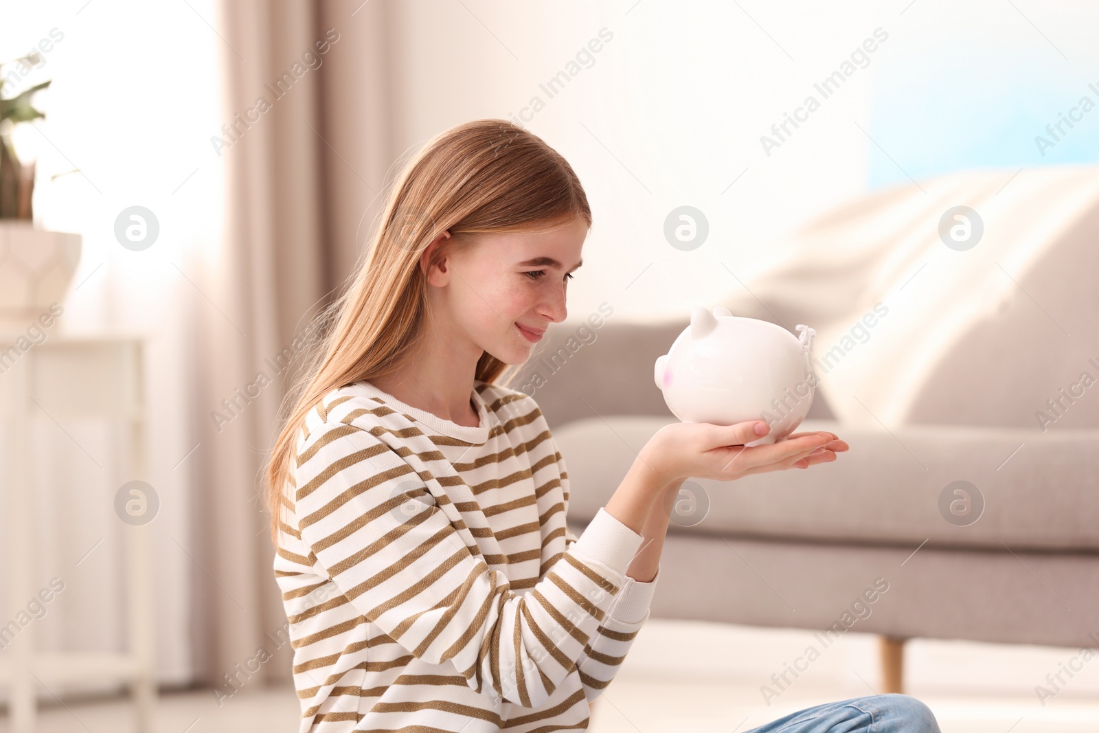 Photo of Teen girl with piggy bank at home