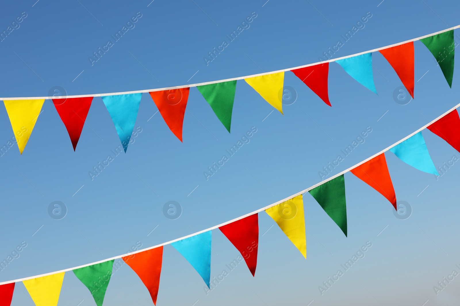 Photo of Buntings with colorful triangular flags against blue sky