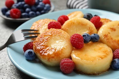 Delicious cottage cheese pancakes with fresh berries and honey on grey table, closeup