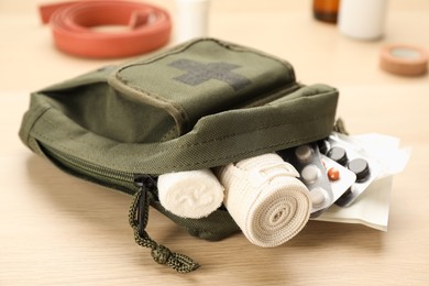 Photo of First aid kit on light wooden table, closeup
