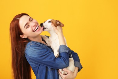 Happy woman with her cute Jack Russell Terrier dog on orange background. Space for text