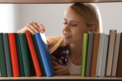 Photo of Woman searching for book on shelf in library
