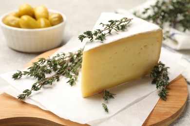 Photo of Piece of tasty camembert cheese and thyme on table, closeup