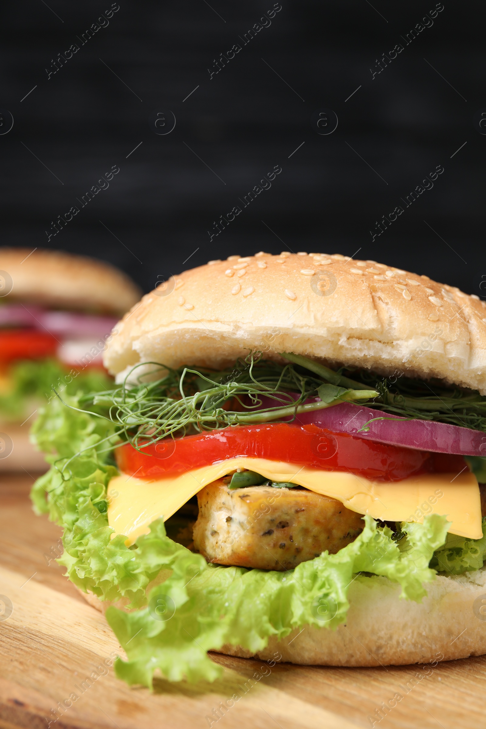 Photo of Delicious burger with tofu and fresh vegetables on wooden table, closeup