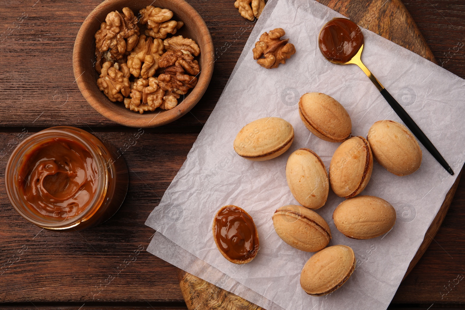 Photo of Delicious nut shaped cookies with boiled condensed milk on wooden table, top view