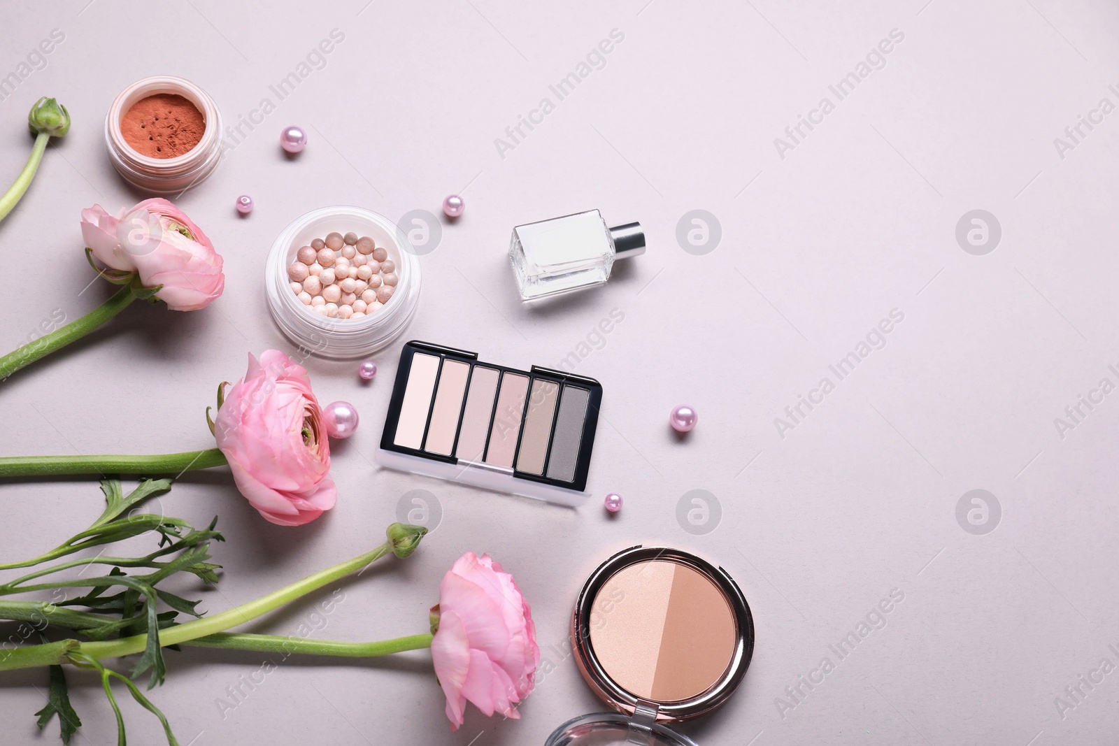 Photo of Flat lay composition with different makeup products and beautiful spring flowers on gray background, space for text