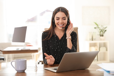 Young woman using video chat on laptop in home office