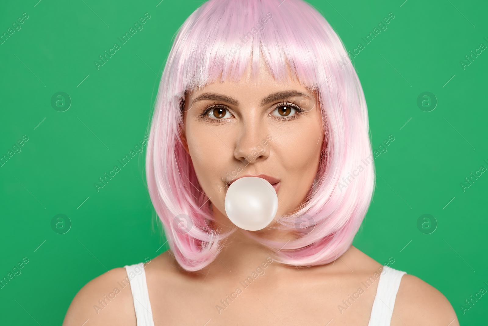 Photo of Beautiful woman blowing bubble gum on green background