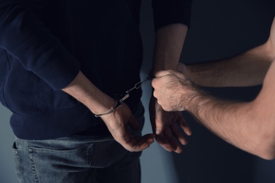 Photo of Man putting handcuffs on drug dealer, closeup view