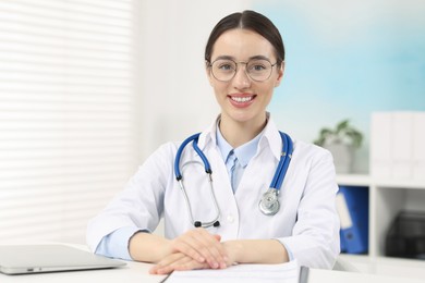 Photo of Medical consultant with glasses and stethoscope at table in clinic