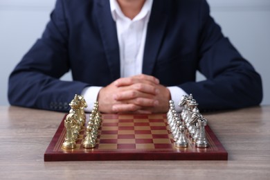 Photo of Man with chess pieces on checkerboard at wooden table before game, closeup