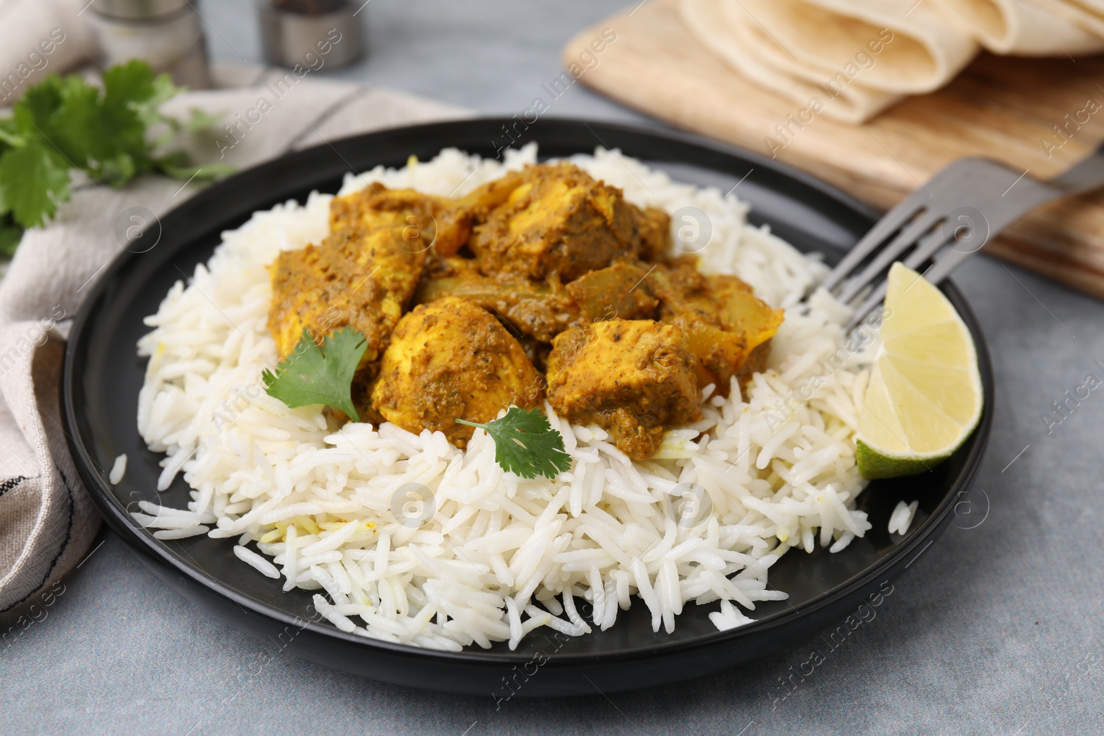 Photo of Delicious chicken curry with rice on grey table, closeup