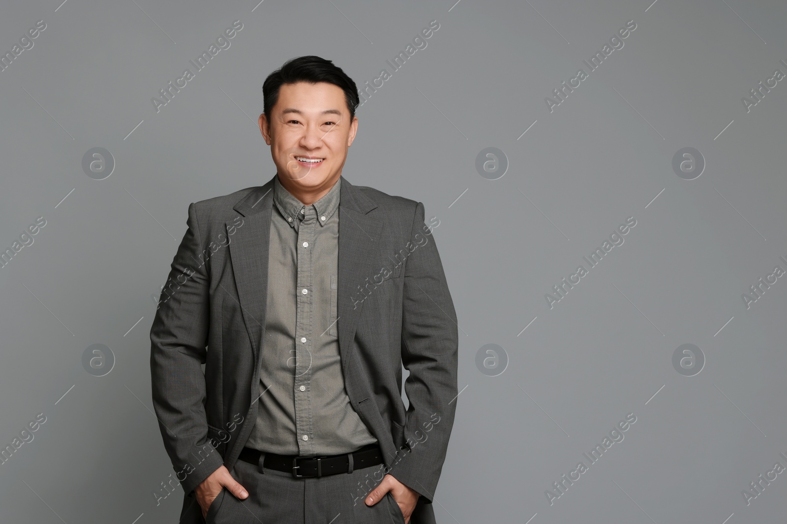 Photo of Portrait of happy businessman on grey background. Space for text