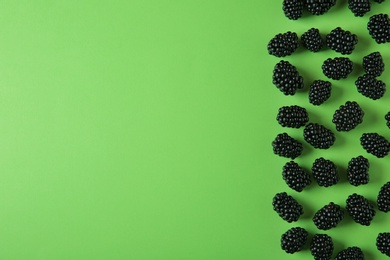 Tasty ripe blackberries on green background, flat lay. Space for text